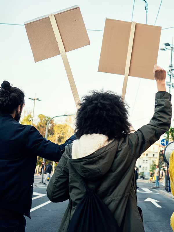 People marching and holding signs viewed from behind