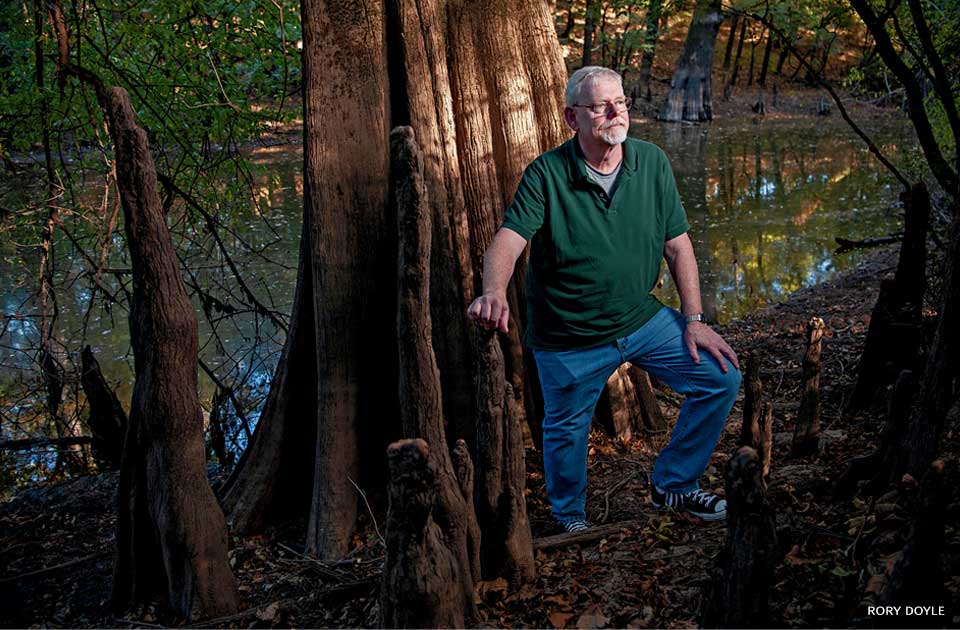 An image of Dr. John Hunt standing for a portrait alongside Bayou Bartholomew.