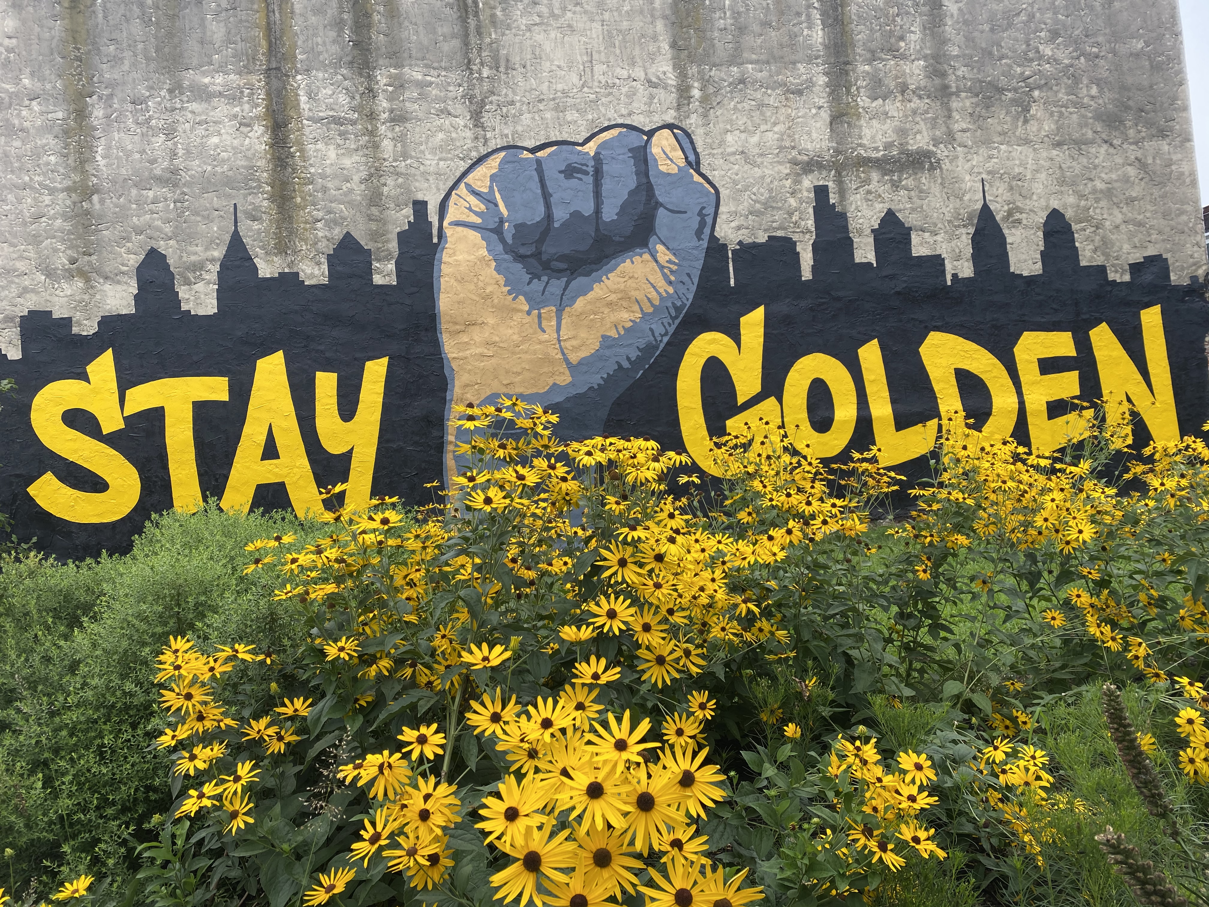 Sweet coneflower, blazing star, and aster planted in front a mural in Strawberry Mansion, Philadelphia.