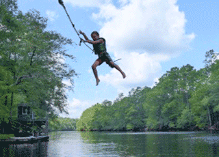 Person swinging from rope swing over body of water